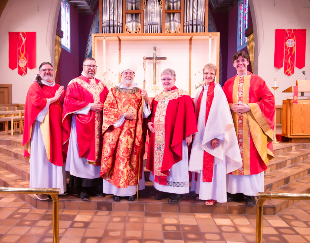 From left to right, the new priests in full vestments who stand with Bishop Skip in the chancel at Grace Grand Rapids are: Barrett Lee, Jonathan Bratt Carle, (Bishop Skip!), Kris Veldheer, Anne Marie Holwerda Warner, and Ryan Lockwood. 