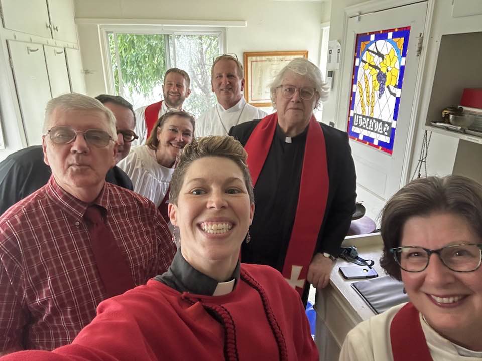 Image Description: A selfie in the sacristy at Trinity Three Rivers with at least five priests, one archdeacon, and two other humans!