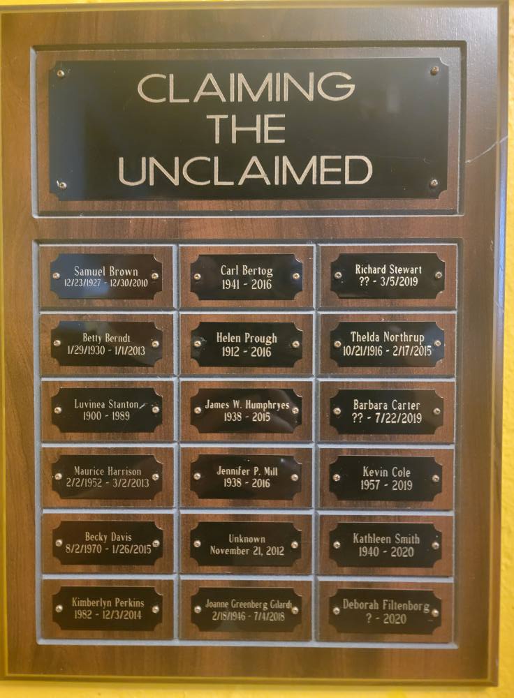 Image Description: A detail shot of a plaque at Epiphany South Haven. The top of the plaque reads "Claiming the Unclaimed," which is the name of the ministry of Epiphany wherein they take the unclaimed cremains from local mortuaries and give the individuals a respectful burial in the parish's memorial garden. The names of claimed individuals and their dates of birth and death (when known) fill the rest of the plaque.