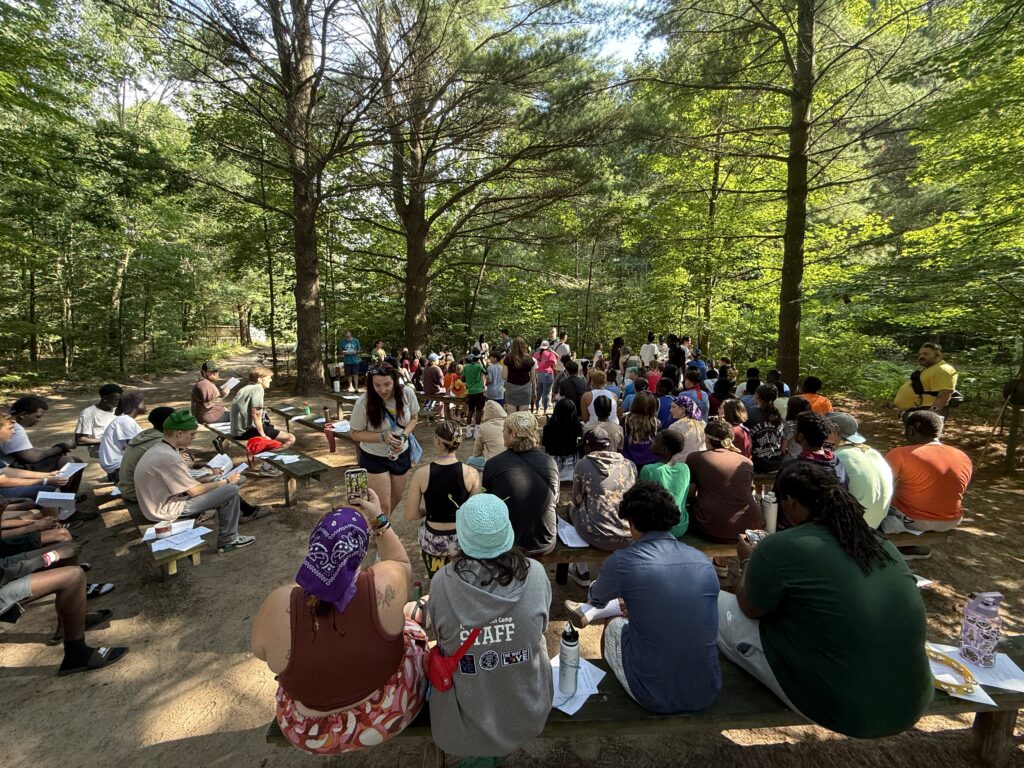 Image Description: A wide shot from the back of the outdoor chapel at EYC as campers and staff alike are gathered for Eucharist.
