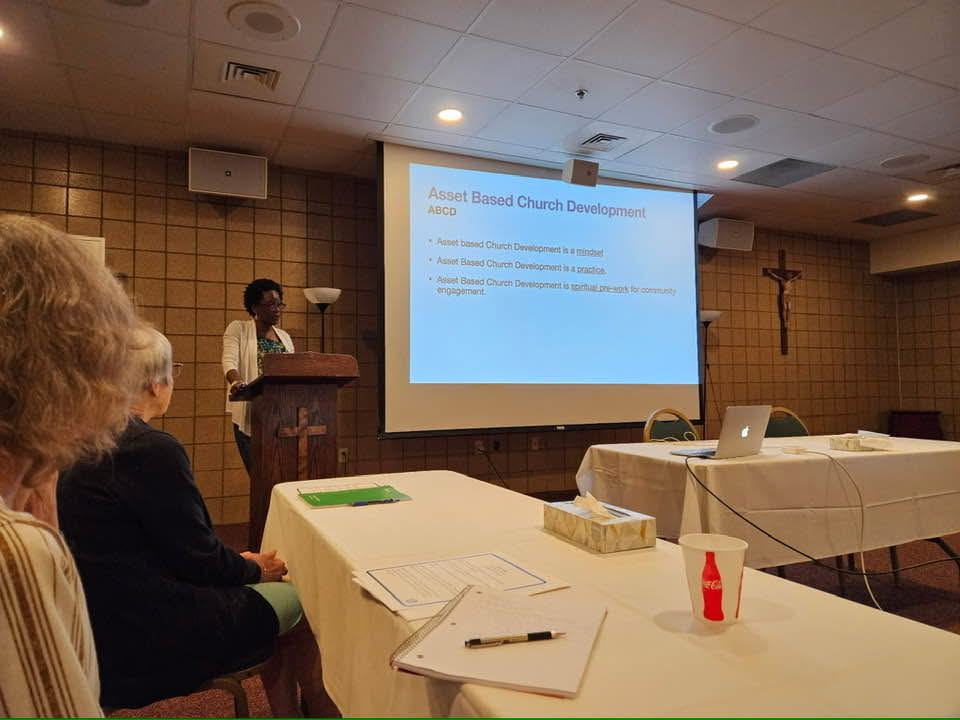 IMAGE DESCRIPTION: An individual is giving a presentation. On the screen, it reads, "Asset Based Church Development"