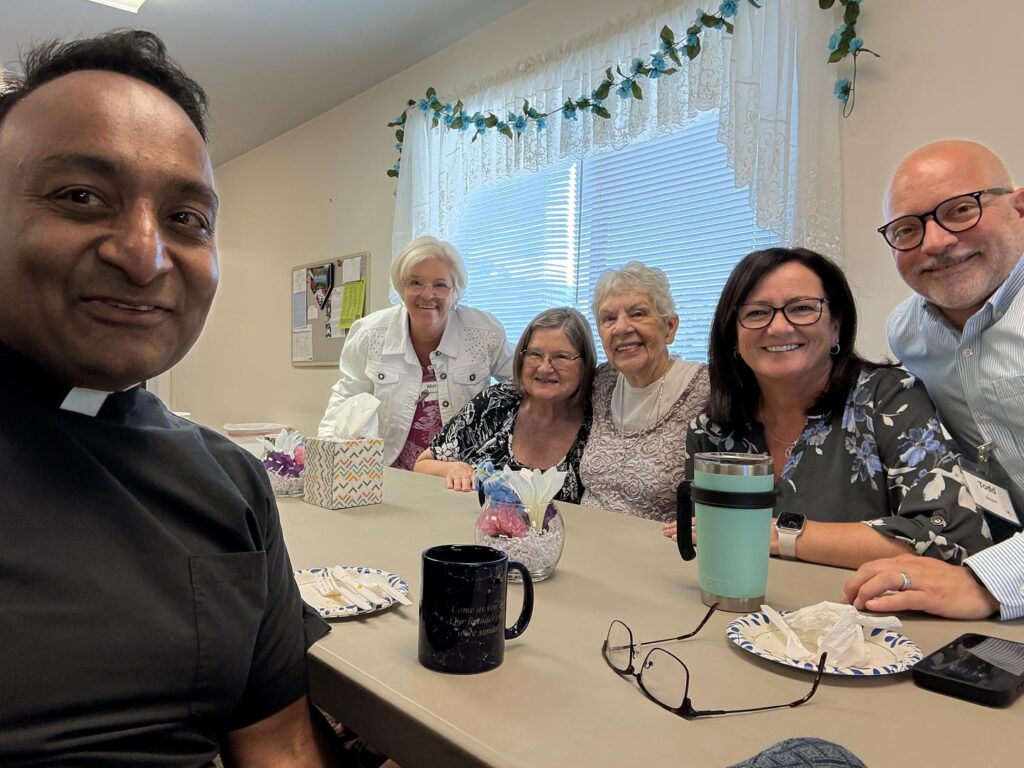 IMAGE DESCRIPTION: A group of people sit together at a table, apparently after a meal. It's a selfie with Canon Sunil and five other smiling people.