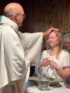 Image description: Fr. Mike Fedewa blesses Kayleigh Gregg, who kneels before him.